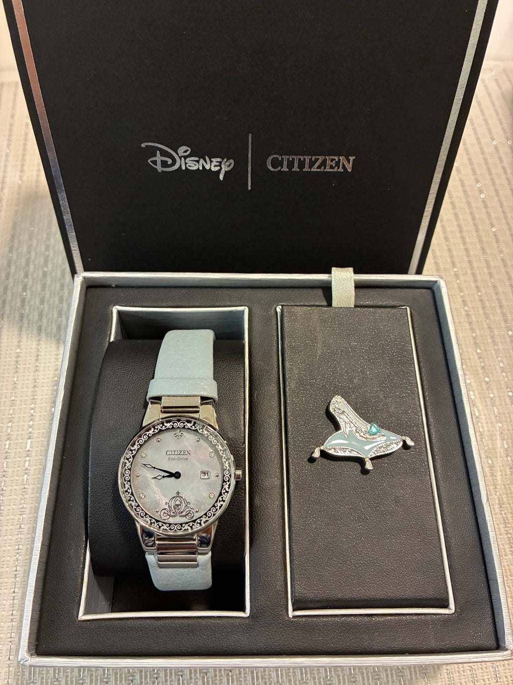 Citizen Eco-Drive Disney Cinderella Box Set features a watch with a crystal-encrusted bezel and a white mother-of-pearl dial